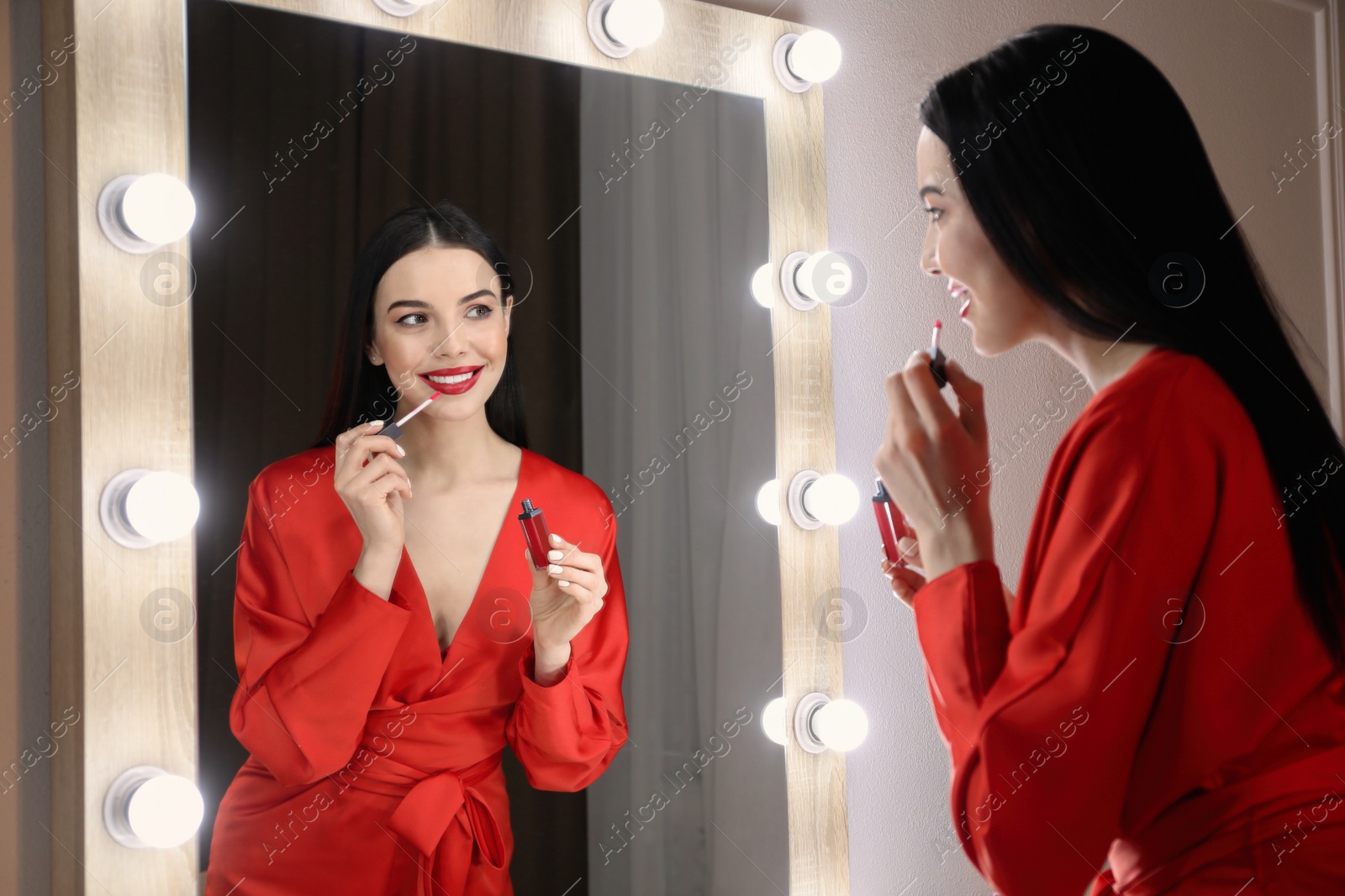 Photo of Beautiful woman applying makeup near mirror in room