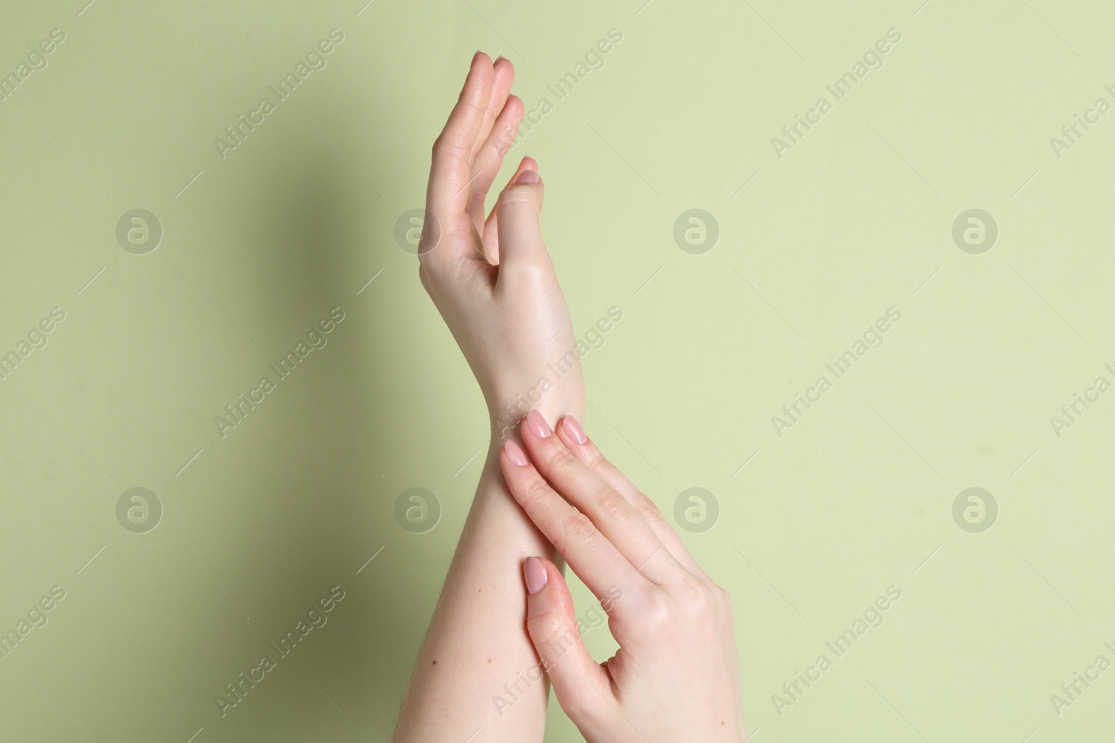 Photo of Woman applying cream on her hand against green background, closeup