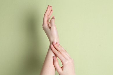 Photo of Woman applying cream on her hand against green background, closeup