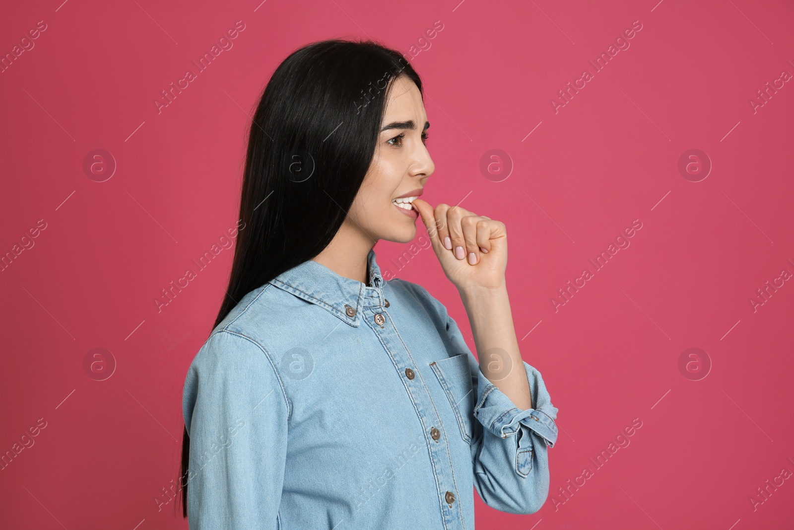 Photo of Young woman biting her nails on pink background. Space for text