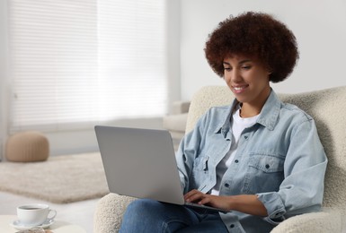 Photo of Young woman using modern laptop in room