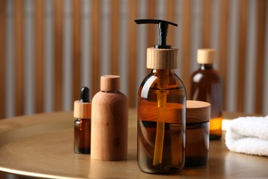 Bottle with dispenser cap and cosmetic products on tray indoors