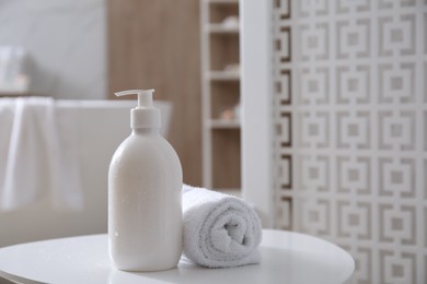 Photo of Bottle of shower gel and fresh towel on white table in bathroom. Space for text