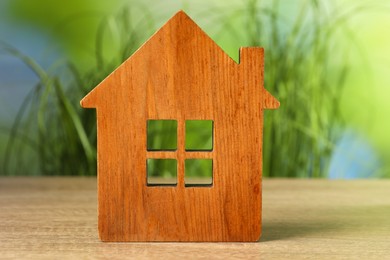 Mortgage concept. House model on wooden table against blurred green background