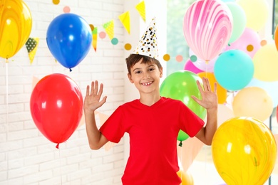 Happy boy near bright balloons at birthday party indoors