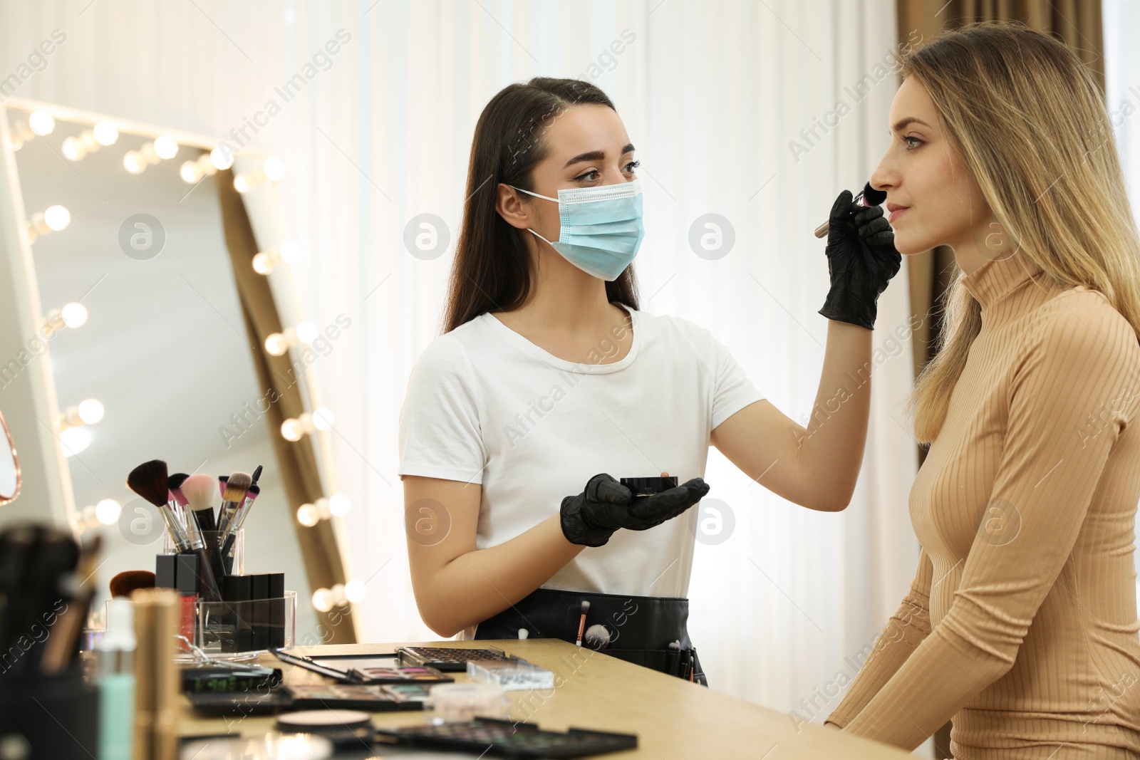 Photo of Professional makeup artist working with client in salon. Beauty services during Coronavirus quarantine