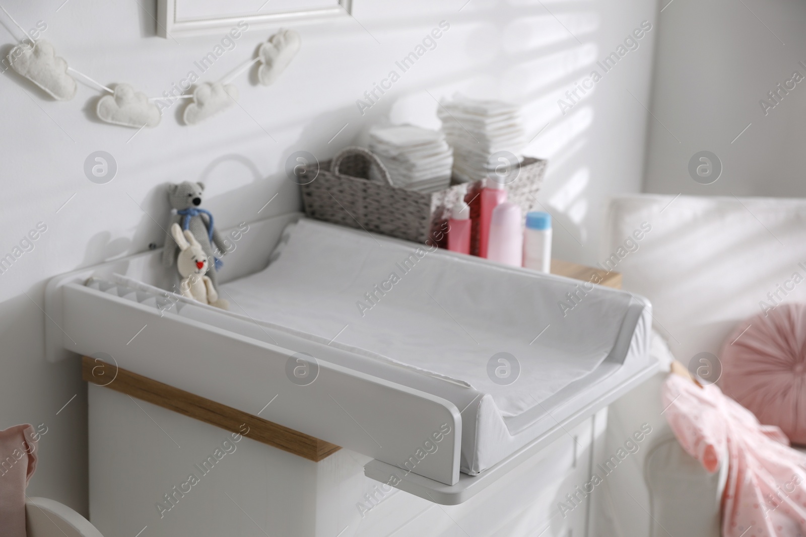 Photo of Chest of drawers with changing tray and pad in baby room. Interior design