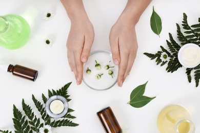 Female dermatologist creating skin care product on white background, top view