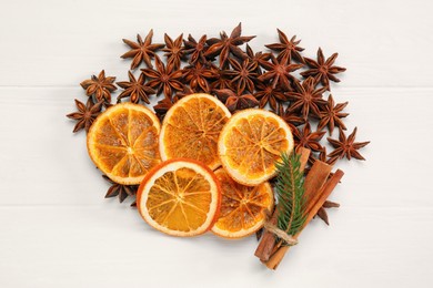 Dry orange slices, cinnamon sticks, fir branch and anise stars on white wooden table, flat lay
