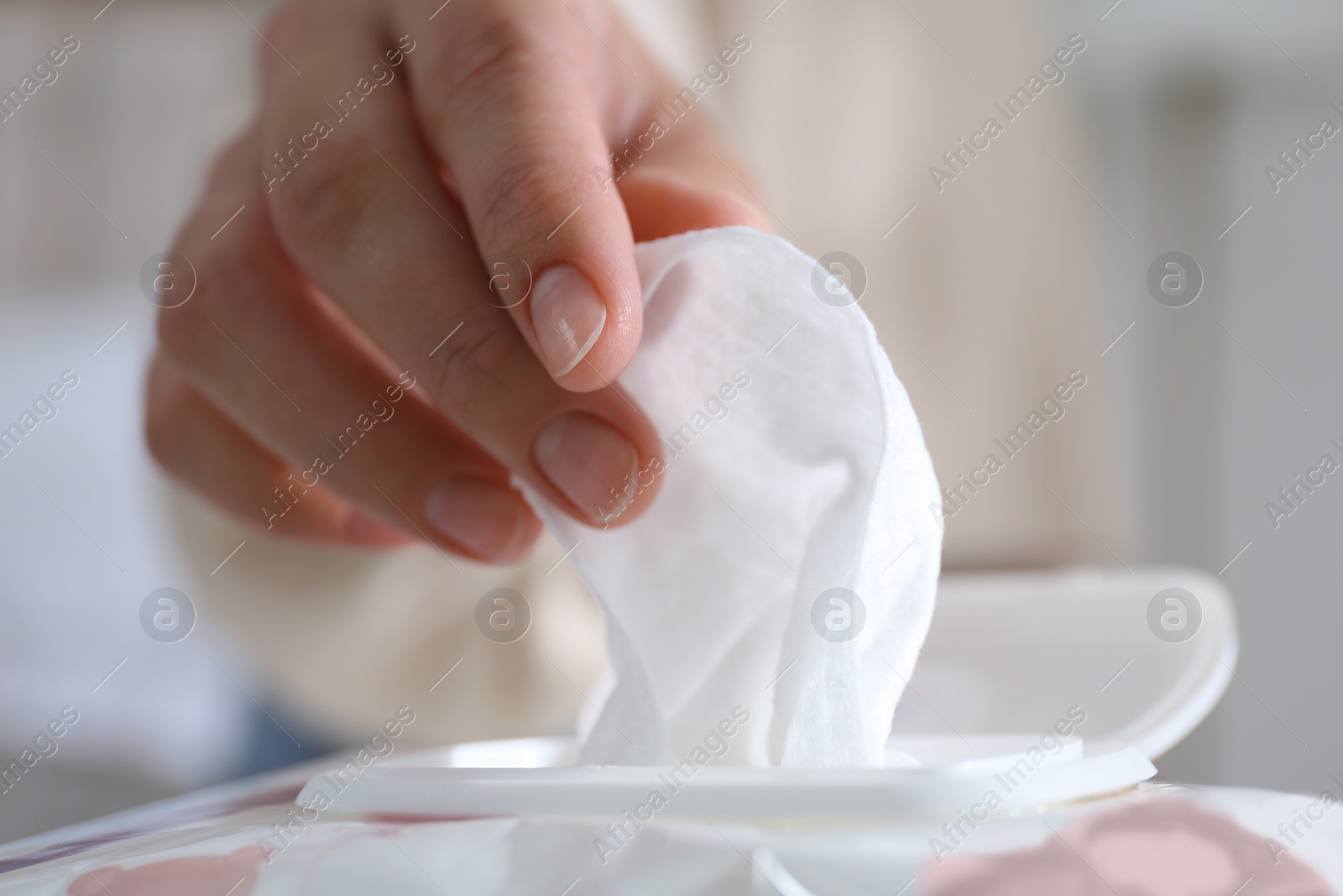 Photo of Woman taking wet wipe out of pack against blurred background, closeup