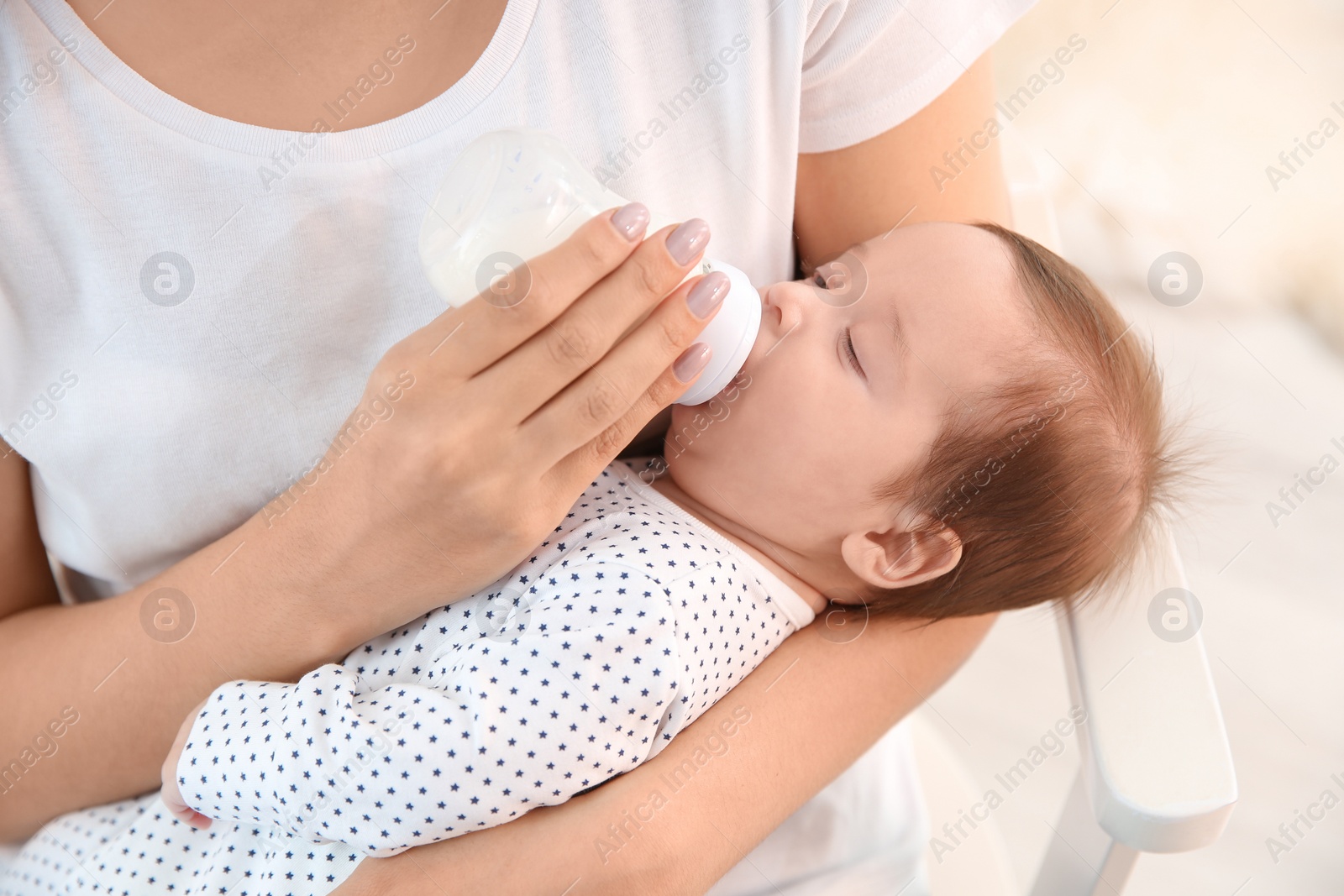 Photo of Woman feeding her baby from bottle at home, closeup