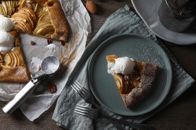 Delicious apple galette served with ice cream on wooden table, flat lay