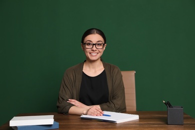 Photo of Portrait of young teacher at table against green background