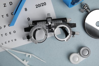 Different ophthalmologist tools on grey background, flat lay