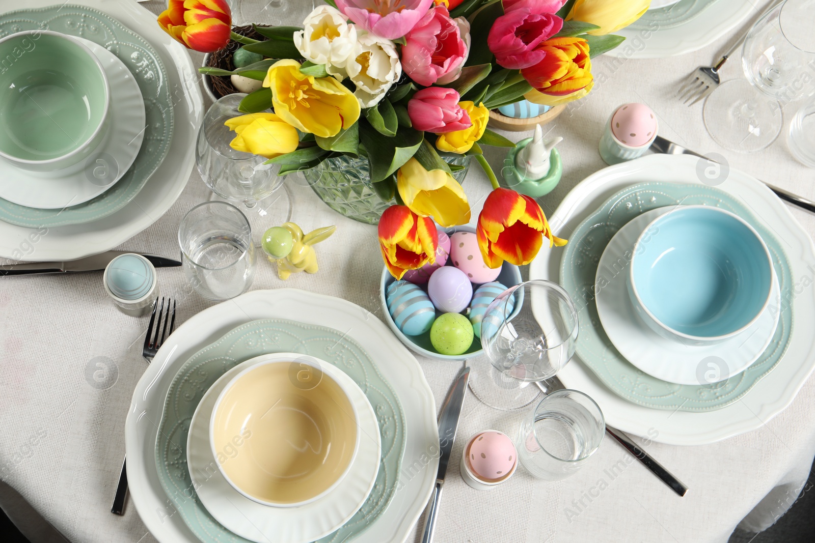 Photo of Festive Easter table setting with beautiful flowers and painted eggs, top view