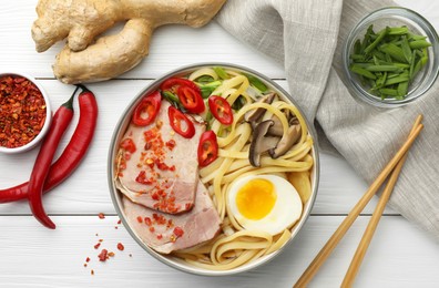 Photo of Delicious ramen in bowl, chopsticks and ingredients on white wooden table, flat lay. Noodle soup