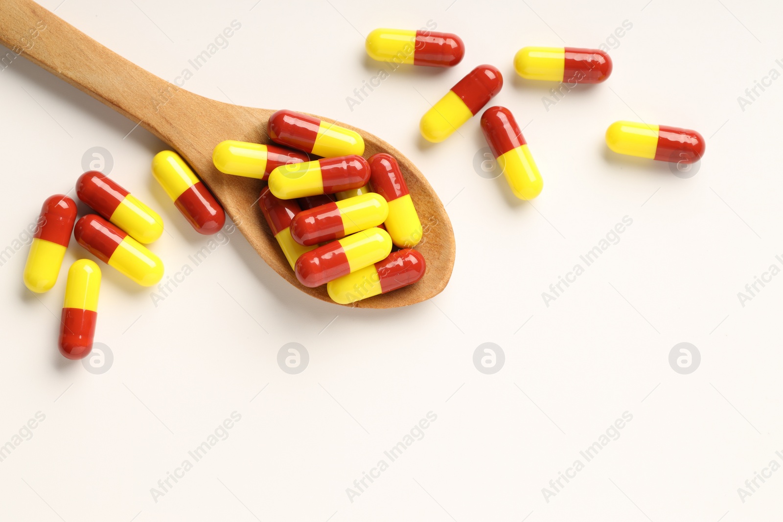 Photo of Antibiotic pills and spoon on white background, top view. Space for text