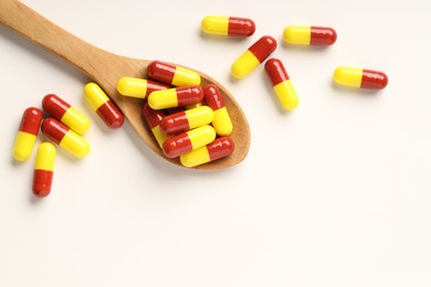 Photo of Antibiotic pills and spoon on white background, top view. Space for text