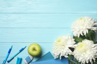 Photo of Flat lay composition with flowers, stationery and apple on light blue wooden background, space for text. Teacher's day