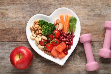 Flat lay composition with plate of products for heart-healthy diet on wooden background