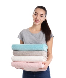 Happy young woman holding clean towels on white background. Laundry day