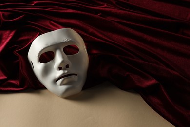 Photo of Theater arts. White mask and red fabric on beige background