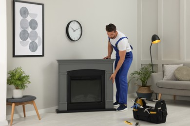 Photo of Professional technician installing electric fireplace in room