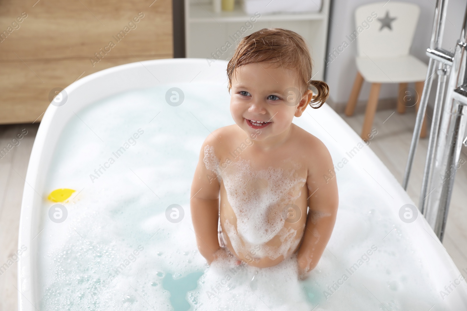 Photo of Cute little girl in foamy bath at home