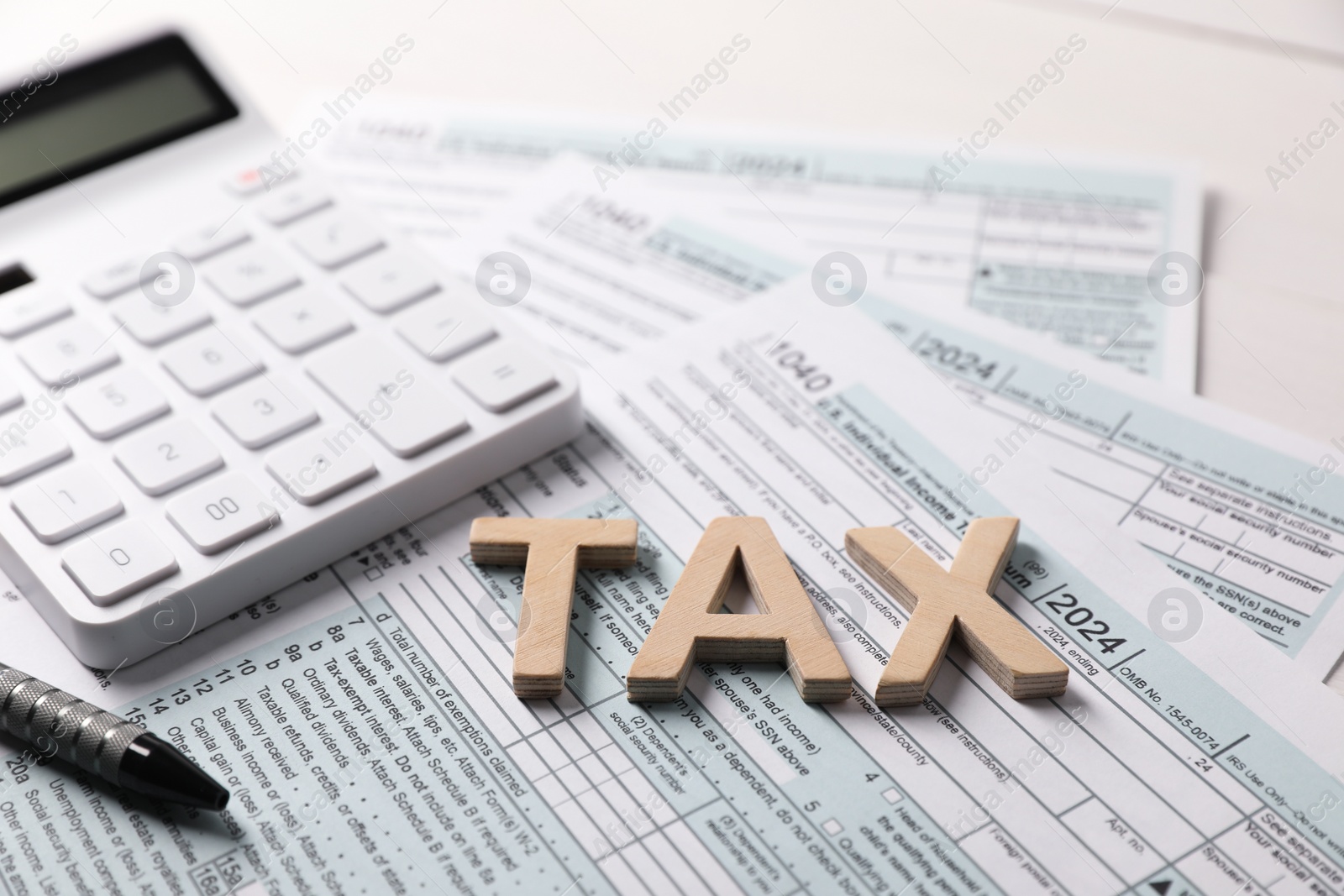 Photo of Word Tax made with wooden letters, calculator and documents on table, closeup