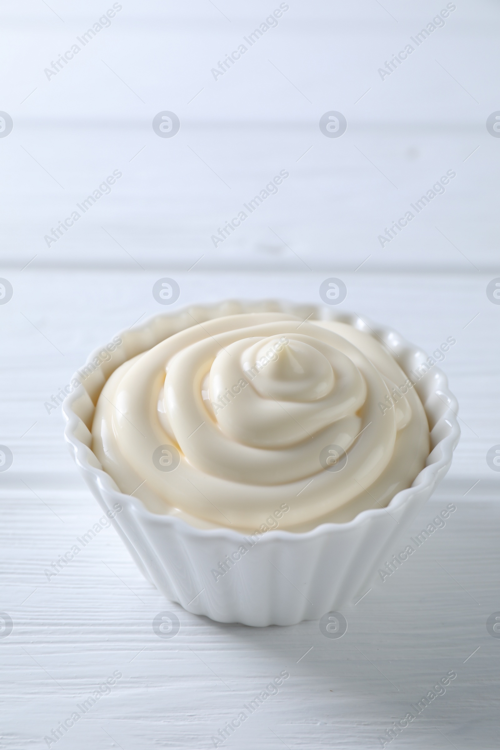 Photo of Fresh mayonnaise sauce in bowl on white wooden table, space for text