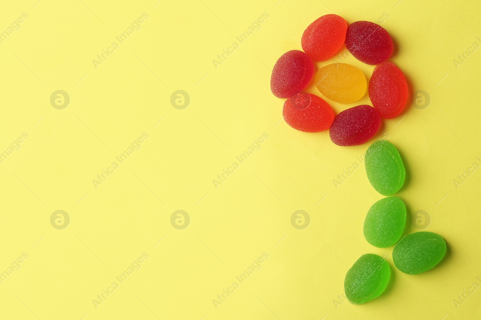 Photo of Flower made with tasty jelly candies on color background, flat lay. Space for text