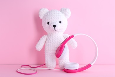 Baby songs. Toy bear and headphones on pink background