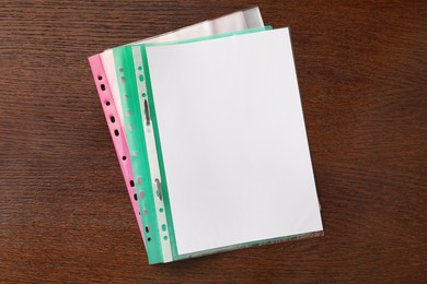 Photo of File folders with punched pockets on wooden table, flat lay. Space for text
