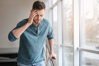 Man suffering from headache near window in office