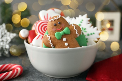 Tasty decorated Christmas cookies in bowl on table. Bokeh effect