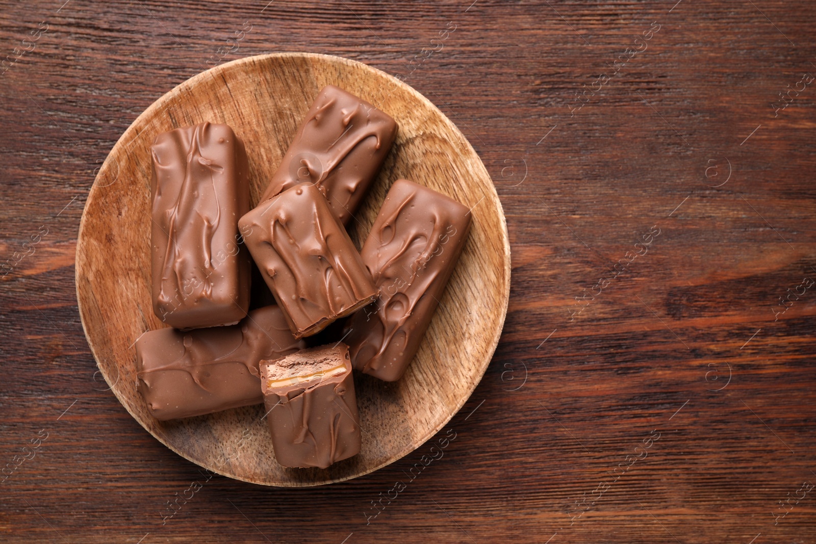 Photo of Tasty chocolate bars with nougat on wooden table, top view. Space for text