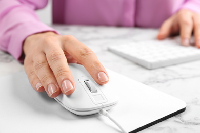 Photo of Woman using modern wired optical mouse at office table, closeup