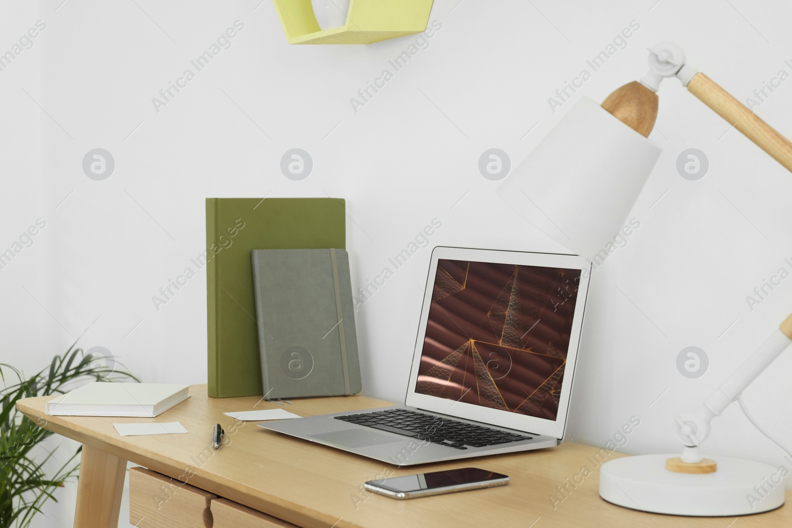 Photo of Cozy workspace with laptop, smartphone and lamp on wooden desk at home