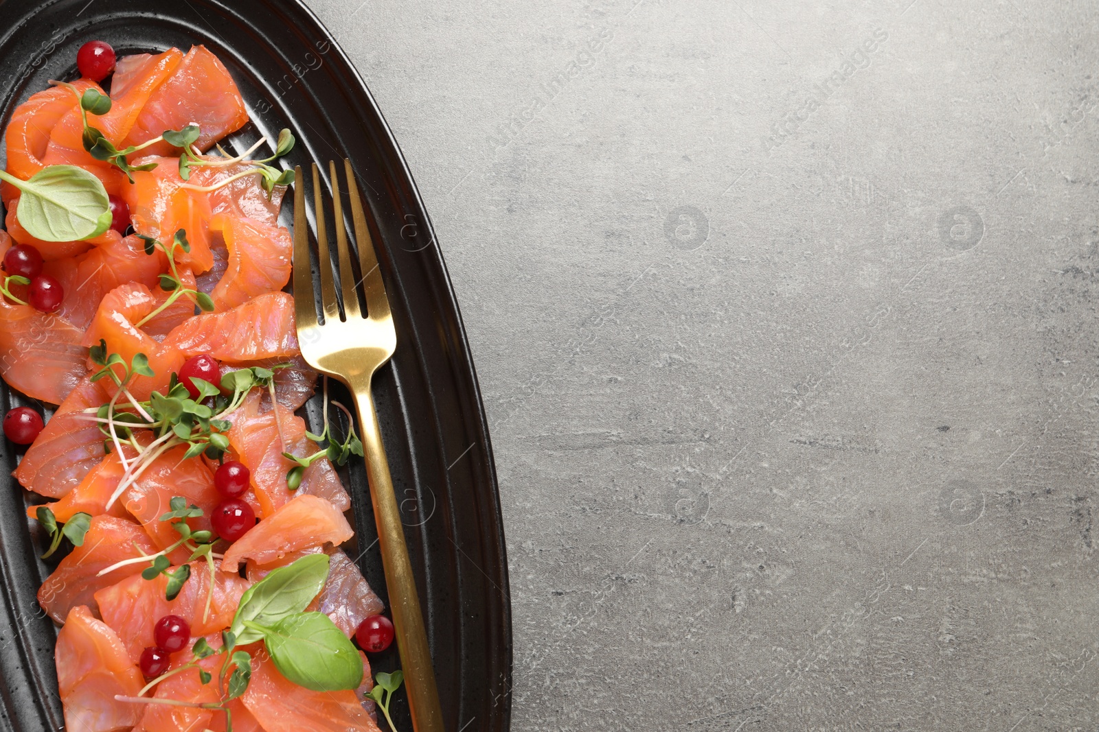 Photo of Delicious salmon carpaccio served on grey table, top view. Space for text