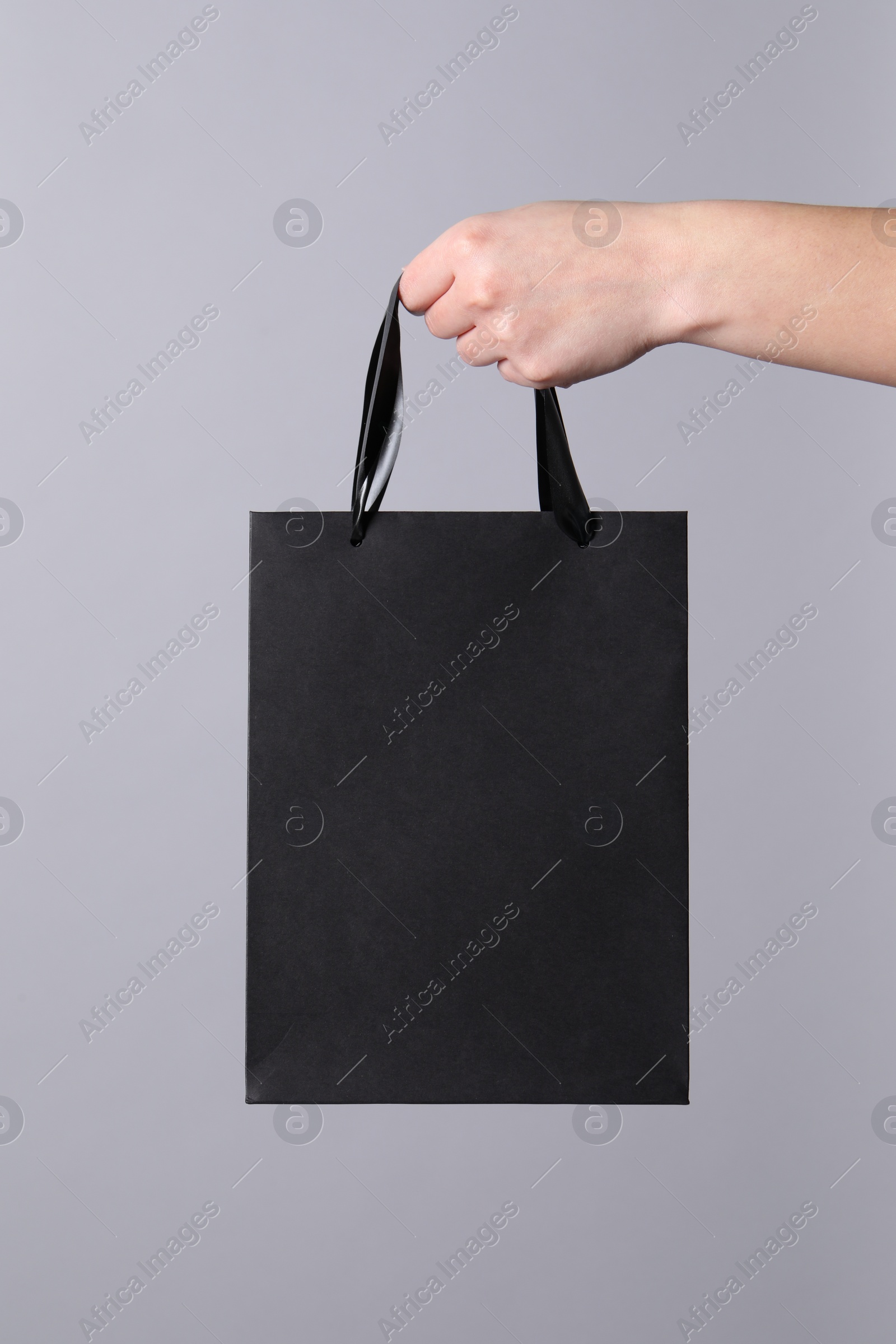 Photo of Woman holding paper shopping bag on grey background, closeup