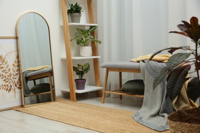 Room interior with wooden furniture, mirror and houseplants. Stylish accessories