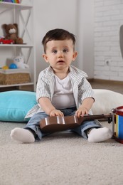 Cute little boy with toy guitar at home