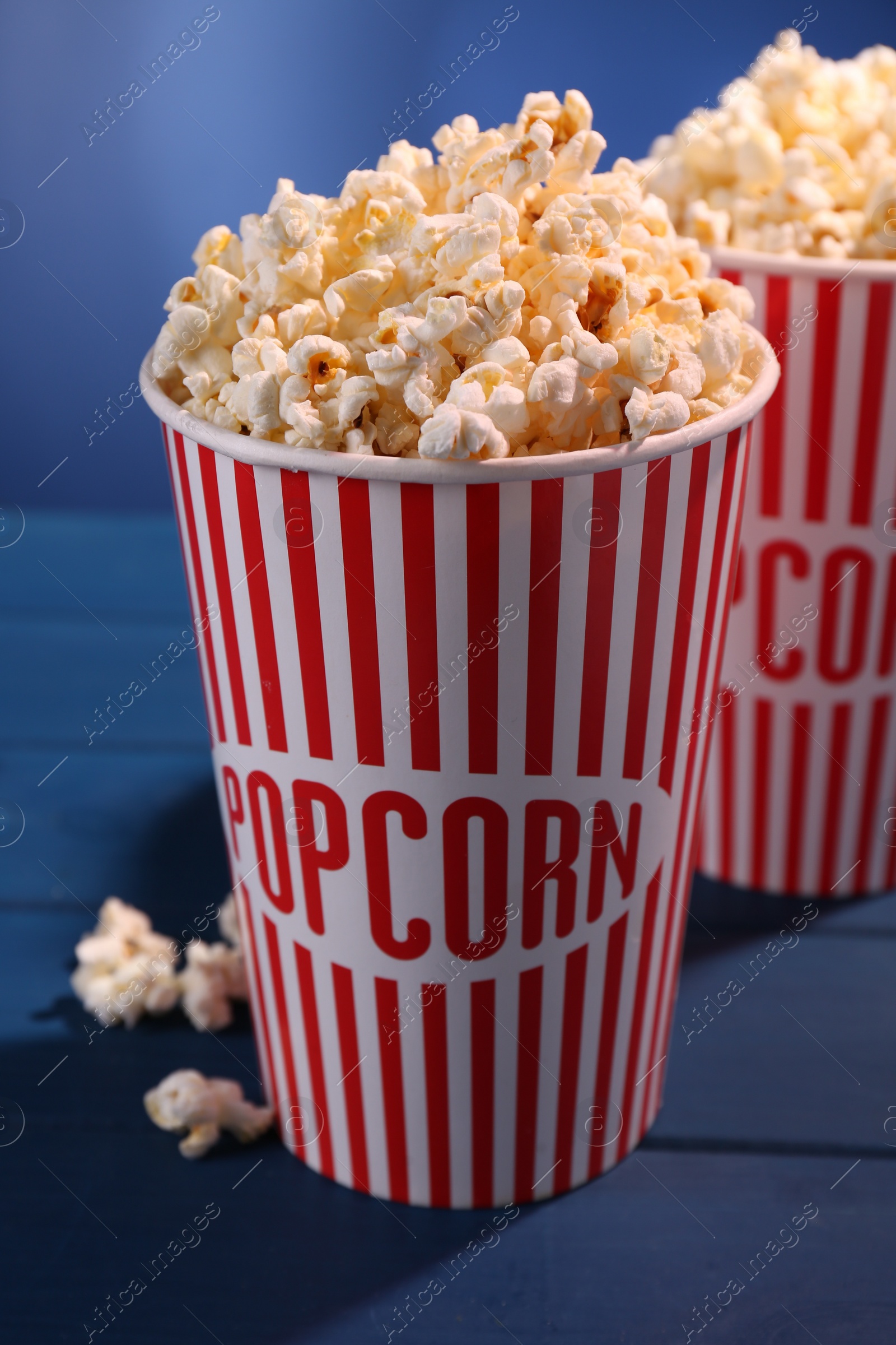 Photo of Delicious popcorn in paper cups on blue wooden table