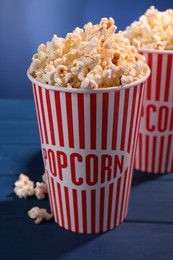 Delicious popcorn in paper cups on blue wooden table