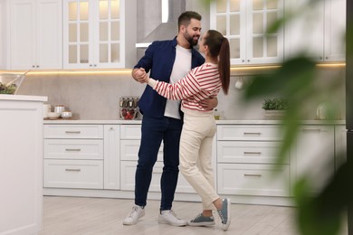 Photo of Happy lovely couple dancing together in kitchen