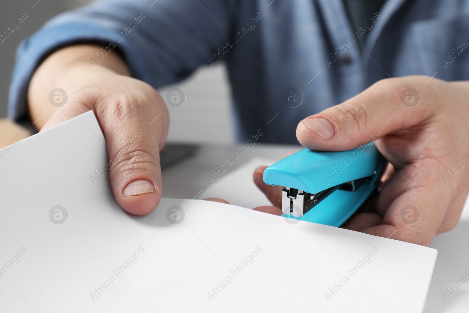 Photo of Man with papers using stapler at table, closeup