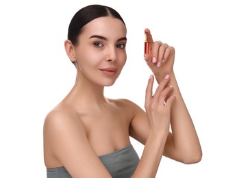 Beautiful young woman holding skincare ampoule on white background