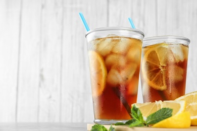 Photo of Glasses of refreshing iced tea against white wooden background. Space for text