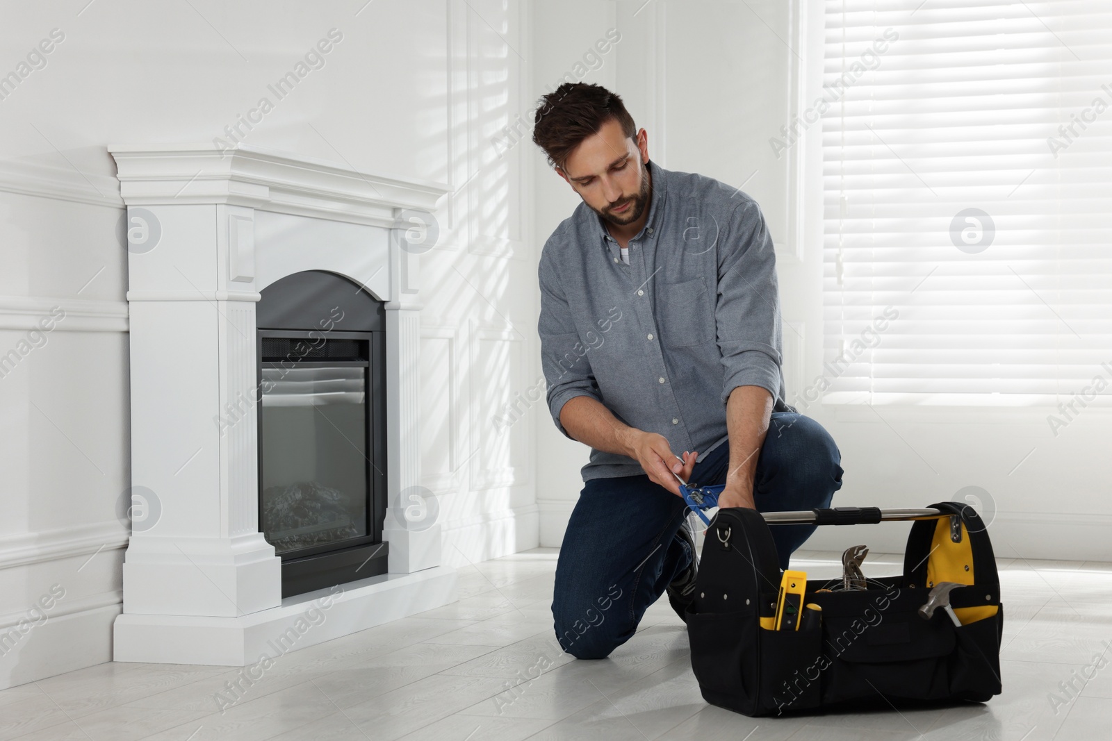 Photo of Man installing electric fireplace near white wall in room