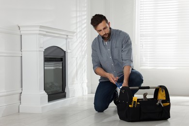 Man installing electric fireplace near white wall in room